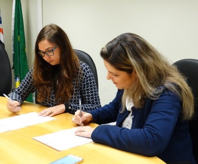 A procuradora Priscila Schreiner e Ana Paula Teodoro Faleiros, gerente jurdica da Band, assinam o Termo de Compromisso.